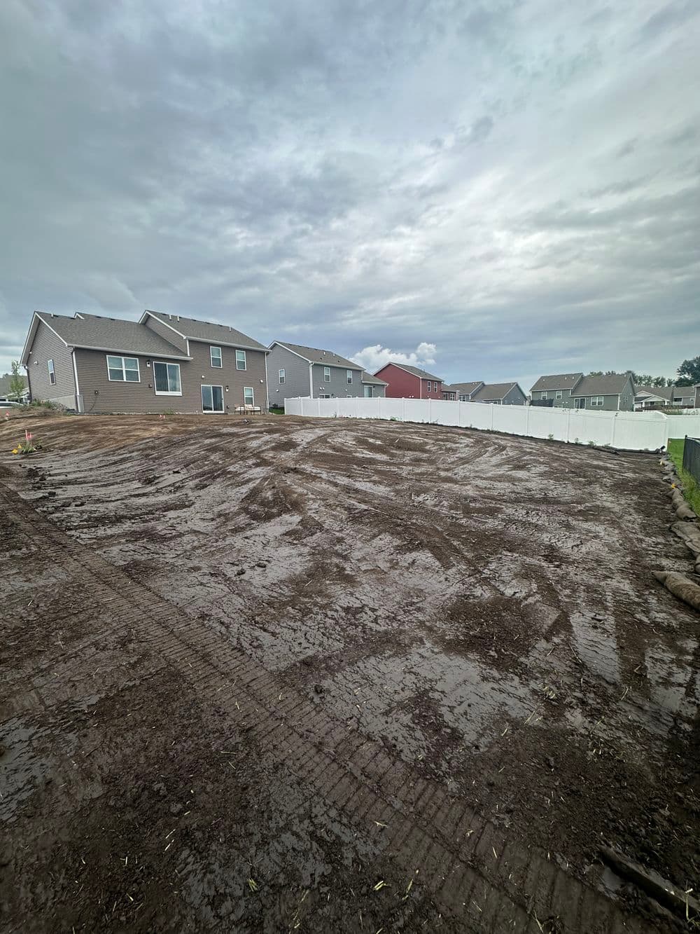 Gravel-covered yard with new construction homes and cloudy sky in the background.